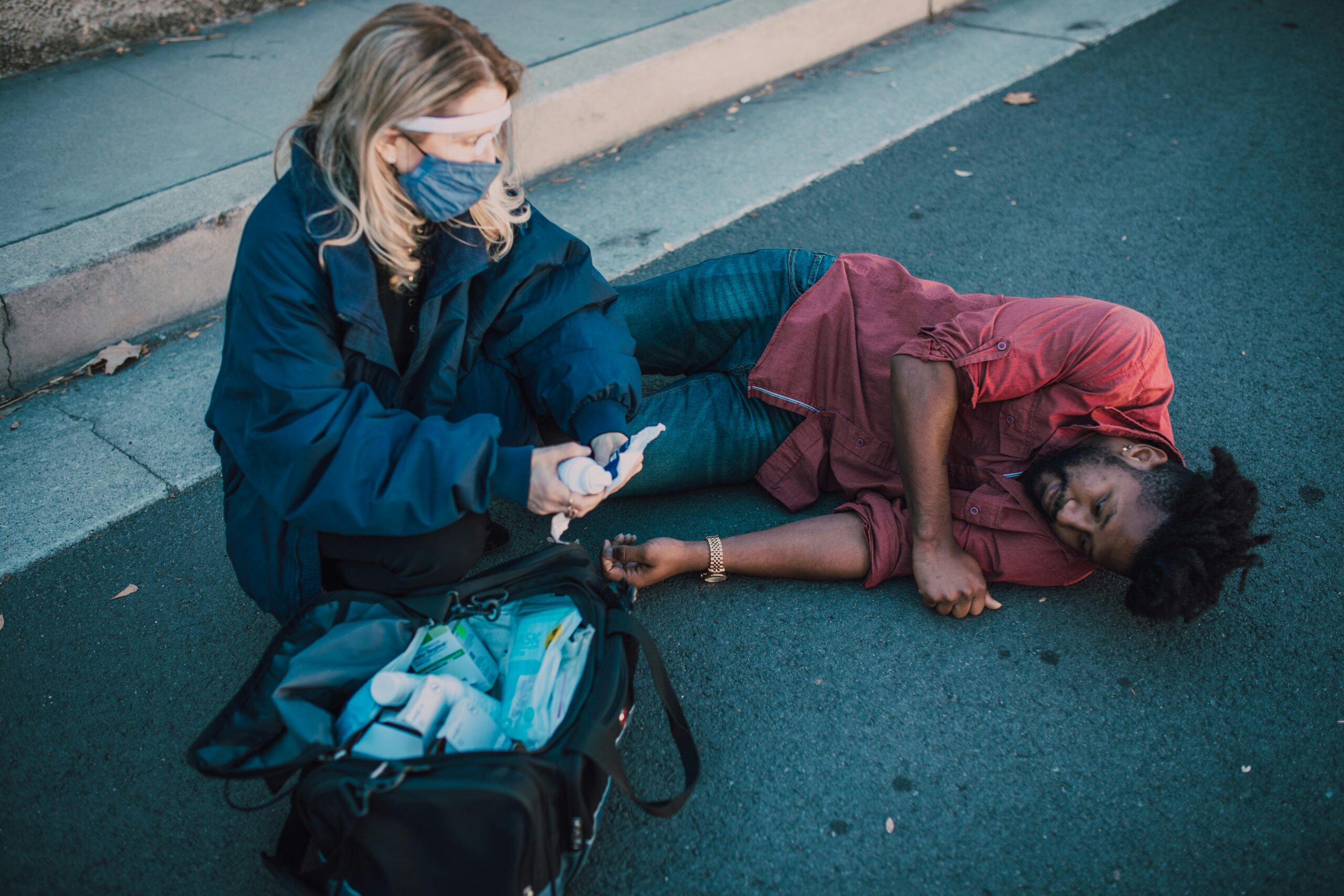 Paramedic provides first aid to injured man lying on roadside.